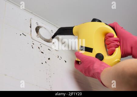 Ein Mann wischt Staub von einem Lüftungsgitter-Techniker, der Luft reinigt Stockfoto