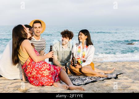 Glückliche multirassische Freunde, die Spaß haben, zusammen mit Getränken am Strand zu jubeln Stockfoto