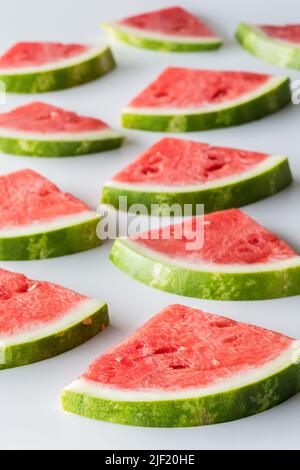 Mehrere frische Wassermelonenscheiben treten in den Hintergrund. Stockfoto