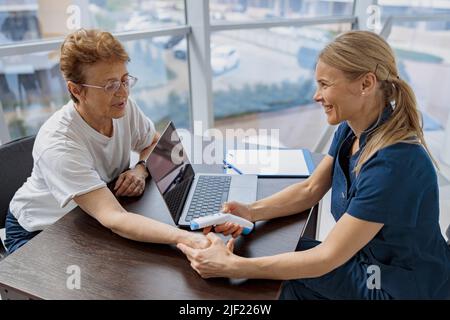 Der Arzt misst die Temperatur des Patienten mit einem berührungslosen Thermometer während eines Termins Stockfoto