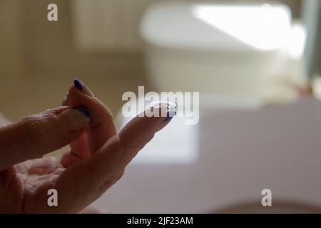 Bild einer Frauenhand, die eine Kontaktlinse auf ihren Finger hält Stockfoto