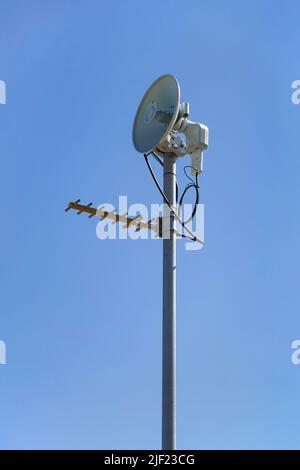 VHF-, UHF-, Mikrowellenantennen am Mast gegen blauen Himmel. Stockfoto