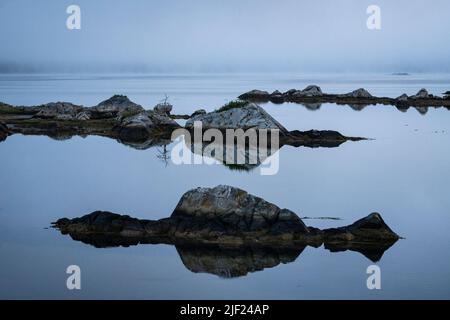 Felsen, die sich auf ruhigem Wasser in der Gezeitenzone entlang des Salt Marsh Trail am östlichen Ufer von Nova Scotia spiegeln. Stockfoto