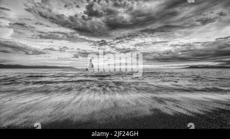 Detaillierte Wolken sind über, wie Ein kleines Boot bewegt sich in Richtung der Shining Light Black and White 16,9 Stockfoto