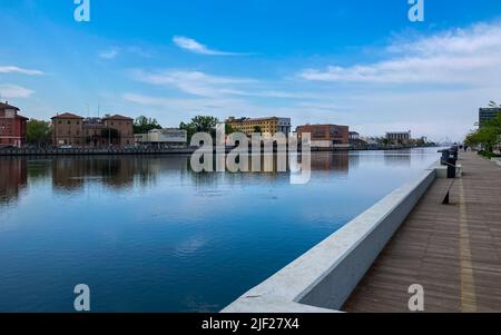 Ravenna, Italien: 10-04-2022: Wunderschöne Gebäude spiegeln sich an einem sonnigen Morgen auf Ravenna's darsena. Ein Dock ist ein abgetrennter Bereich mit Wasser, für den verwendet wird Stockfoto