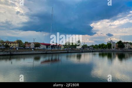 Ravenna, Italien: 10-04-2022: Wunderschöne Gebäude spiegeln sich an einem sonnigen Morgen auf Ravenna's darsena. Ein Dock ist ein abgetrennter Bereich mit Wasser, für den verwendet wird Stockfoto