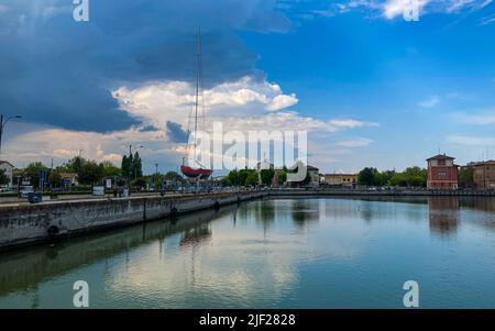 Ravenna, Italien: 10-04-2022: Wunderschöne Gebäude spiegeln sich an einem sonnigen Morgen auf Ravenna's darsena. Ein Dock ist ein abgetrennter Bereich mit Wasser, für den verwendet wird Stockfoto