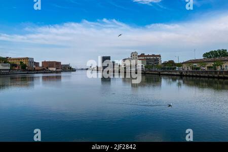 Ravenna, Italien: 10-04-2022: Wunderschöne Gebäude spiegeln sich an einem sonnigen Morgen auf Ravenna's darsena. Ein Dock ist ein abgetrennter Bereich mit Wasser, für den verwendet wird Stockfoto