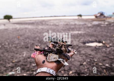 Mombasa, Kenia. 26.. Juni 2022. Man sieht die Hand eines Mannes, der Plastikmüll hält, der am Ufer in der Altstadt von Lamu gesammelt wurde. Die Verschmutzung durch menschliche Aktivitäten hat die Ozeane negativ beeinflusst. Der kenianische Präsident Uhuru Kenyatta sagte in seiner Rede während der laufenden Ozeankonferenz in Lissabon, Portugal, dass die Plastikverschmutzung mindestens 700 Arten von Meereslebewesen krank macht und kontaminiert, und forderte dringende globale Maßnahmen zum Schutz unserer Ozeane. Die Ozeankonferenz wird von den Regierungen Portugals und Kenias gemeinsam ausgerichtet. Kredit: SOPA Images Limited/Alamy Live Nachrichten Stockfoto