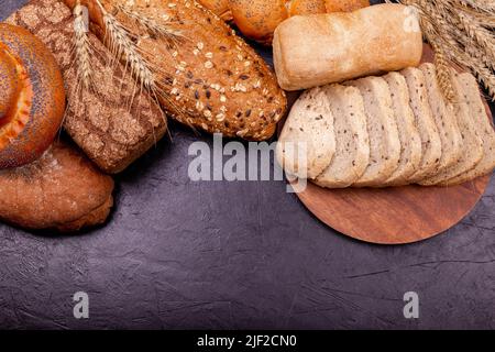 Verschiedene leckere Brötchen und Brote mit Korn Nahaufnahme auf grauem Hintergrund. Stockfoto