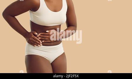 Schwarze Frau kämpft mit Bauchschmerzen Stockfoto