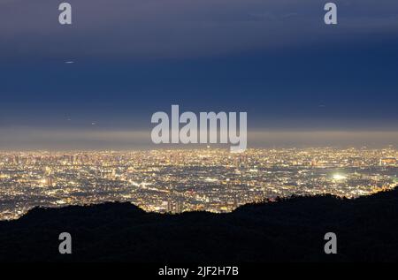 Dunkler Hügel mit Blick auf die ausgedehnte Stadt in der Nacht Stockfoto