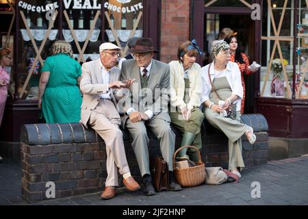 Dudley, West Midlands-vereinigtes Königreich Juli 13 2019 Gruppe von vier Rentnern zwei Männer zwei Frauen sitzen an einer Wand vor einem Geschäft reden WW2 Konz Stockfoto