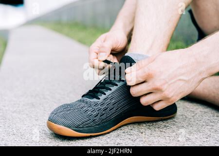 Nahaufnahme von Sportlern, die beim Laufen im Freien Schuhe binden Stockfoto