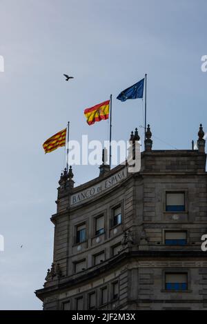 Barcelona, Katalonien, Spanien - 22. Mai 2022: Flaggen von Katalonien, Spanien und der Europäischen Union auf dem Bankgebäude. Das Gebäude der Bank of Spain. Spanisch Stockfoto