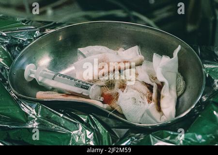 15. Mai 2022, Pokrovskoe, Region Dnepropetrovsk, Ukraine: Gebrauchte Handtücher mit Blut und Injektion von einem Patienten. Das Militärkrankenhaus in Pokrovskoe, Region Dnepropetrovsk, stabilisiert die Bedingungen der verwundeten Soldaten von der Front aus. Danach werden sie in größere Krankenhäuser in Zaporizhia und Dnipro überführt. Die Regionen Saporischschja und Dnipro sind seit Kriegsbeginn ein Schwerpunkt der russischen Angriffe. (Bild: © Lara Hauser/SOPA Images via ZUMA Press Wire) Stockfoto