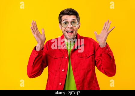 Foto von beeindruckt jungen Brunet Kerl Palmen bis tragen rote Hemd Brille isoliert auf gelbem Hintergrund Stockfoto