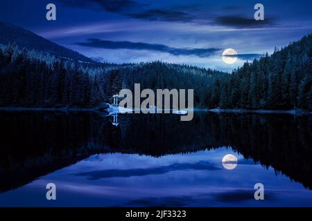 Ruhige Landschaft mit See im Sommer in der Nacht. Waldspiegelung im ruhigen Wasser. Szenische Reise Hintergrund. Grüne Outdoor-Naturszene in voller moo Stockfoto