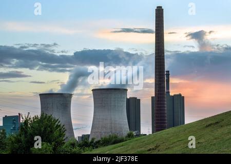Schwerkraftwerksindustrie, Schornstein und Türme mit Verschmutzung im Stahlwerk HKM in Duisburg, Deutschland gegen bewölkten Himmel bei Sonnenuntergang, Kopierraum, s Stockfoto