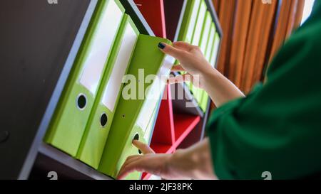 Secretary nimmt Business Folder mit Dokumenten aus dem Schrank Stockfoto