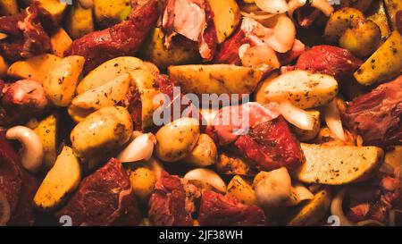 Oben close up view rohes Fleisch mit Kartoffeln im Backblech vor dem Kochen gewürzt mit Kräutern Stockfoto