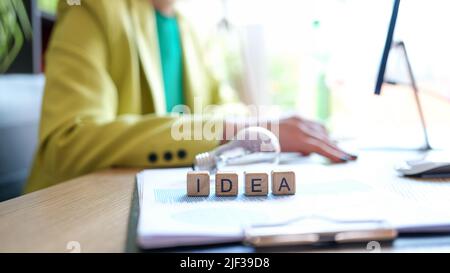 Kreative Frau mit Glühbirne arbeiten am Computer auf Wort Idee Nahaufnahme Stockfoto