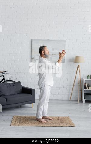 Seitenansicht des barfuß-Yogameisters, der in Baumhaltung mit betenden Händen zu Hause meditiert Stockfoto