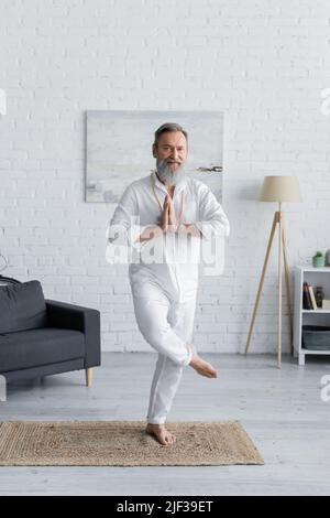Die ganze Länge des barfuß-Gurumans meditiert mit betenden Händen in Baumhaltung zu Hause Stockfoto