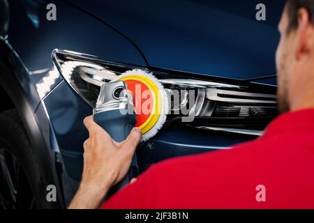 Mann polieren Autoscheinwerfer mit polnischer Maschine. Wiederherstellung Fahrzeugbeleuchtung Stockfoto