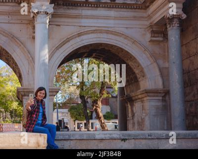 Reise nach Türkei. Glückliche asiatische Touristenreisende mit Rucksack Spaziergänge in der Altstadt. Frau macht Selfie-Fotos vor dem Hintergrund von Hadrians Tor - Stockfoto