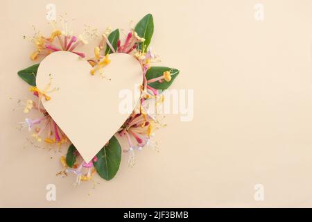 Herzform aus farbigem Karton versteckt Caprifoi Blumen. Romantische Kulisse mit schönen Blumen. Stockfoto