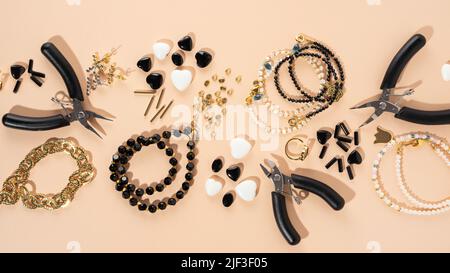 Werkzeuge und Zubehör für DIY-Schmuck am Arbeitsplatz. Flach lag auf beigem Hintergrund. Kreative flache Lay-Komposition, Banner, Draufsicht. Heimwerker-Hobby Stockfoto