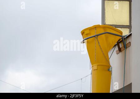 Gelbe Schutthülle oder Schutthülle an der Fassade des alten weißen Hauses helfen bei der Renovierung und Renovierung des alten Grundstücks für saubere Schutthülle Stockfoto