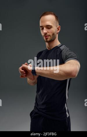 Porträt eines Sportlers, der nach dem Training im Fitnessstudio die Herzfrequenz auf dem Fitness-Trekker überprüft Stockfoto