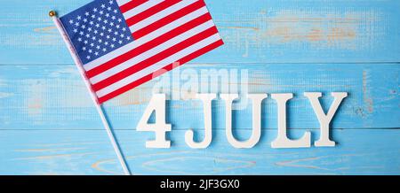 Text des 4. Juli und Flagge der Vereinigten Staaten von Amerika auf Holztisch Hintergrund. USA Unabhängigkeitsfeiertag und Festungskonzepte Stockfoto