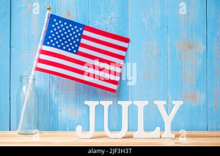 Juli Text und Flagge der Vereinigten Staaten von Amerika auf Holztisch Hintergrund. USA Unabhängigkeitsfeiertag und Festungskonzepte Stockfoto