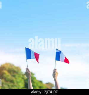 Hand hält Frankreich Flagge auf blauem Himmel Hintergrund. Feiertag des französischen Nationaltages, Bastille Tag und glückliche Feier Konzepte Stockfoto