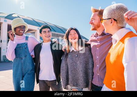 Fröhliche Teenager-Freunde in Schattierungen, die auf der Straße reden. Junge multiethnische Freunde sprechen und verbringen Zeit miteinander. Stockfoto