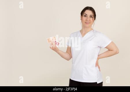 Lächelnde weibliche medizinische professionelle Physiotherapeutin präsentiert Patch Kinesio Cross Tapes für Anti-Cellulite-Hautlifting Stockfoto