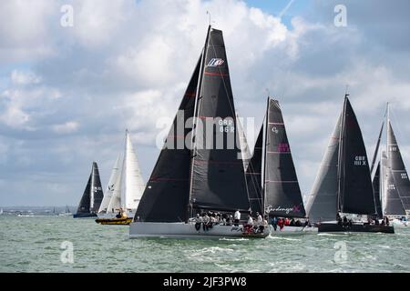 Die Teilnehmer stehen an und passieren das gelbe Harbour Patrol Boat, um das jährliche Round the Island-Yacht-Rennen des Isle of Wight Sailing Club zu starten Stockfoto