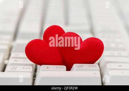 Nahaufnahme eines roten Herzpaares auf der Tastatur. Internet-Dating-Konzept. Stockfoto