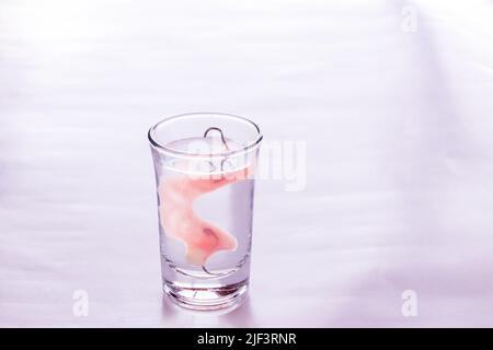 Close up Acryl Prothesen in ein Glas Wasser getaucht, Tisch im Schlafzimmer. Heller, einfacher Hintergrund. Stockfoto