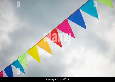 Band mit mehrfarbigen dreieckigen Fahnen am Himmel. Festliche Dekorationen. Gut gelaunt. Geburtstag. Jahrestage. Stockfoto