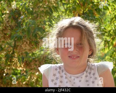 Mädchen, das unter dem Baum spielt. Schönes Porträt eines Kindes. Kinderportrait. Stockfoto