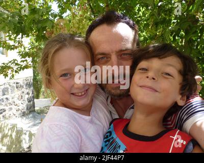 Ein bärtiger Vater umarmt seine Tochter und seinen Sohn Stockfoto