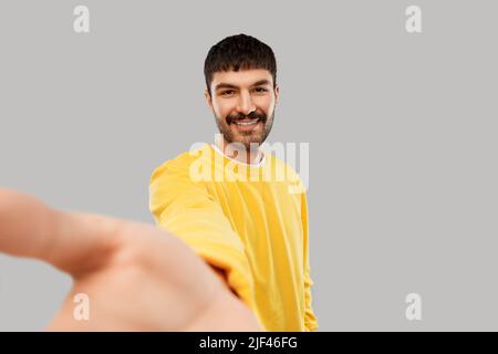 Glücklicher junger Mann im gelben Sweatshirt, der Selfie macht Stockfoto