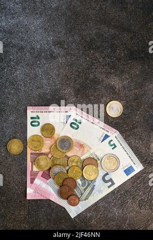 Eurobanknoten und Euromünzen Eurocents liegen auf einem dunklen Steinhintergrund, Krise und Inflation Stockfoto