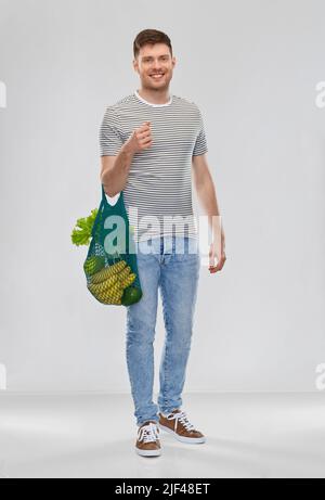 Glücklicher Mann mit Lebensmitteln in wiederverwendbarer Netztasche Stockfoto