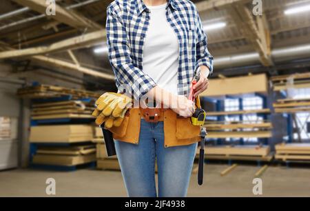 Arbeiterin mit Werkzeugen am Gürtel in der Fabrik Stockfoto