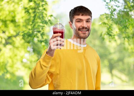 Glücklicher Mann mit Tomatensaft in der Tasse zum Mitnehmen Stockfoto